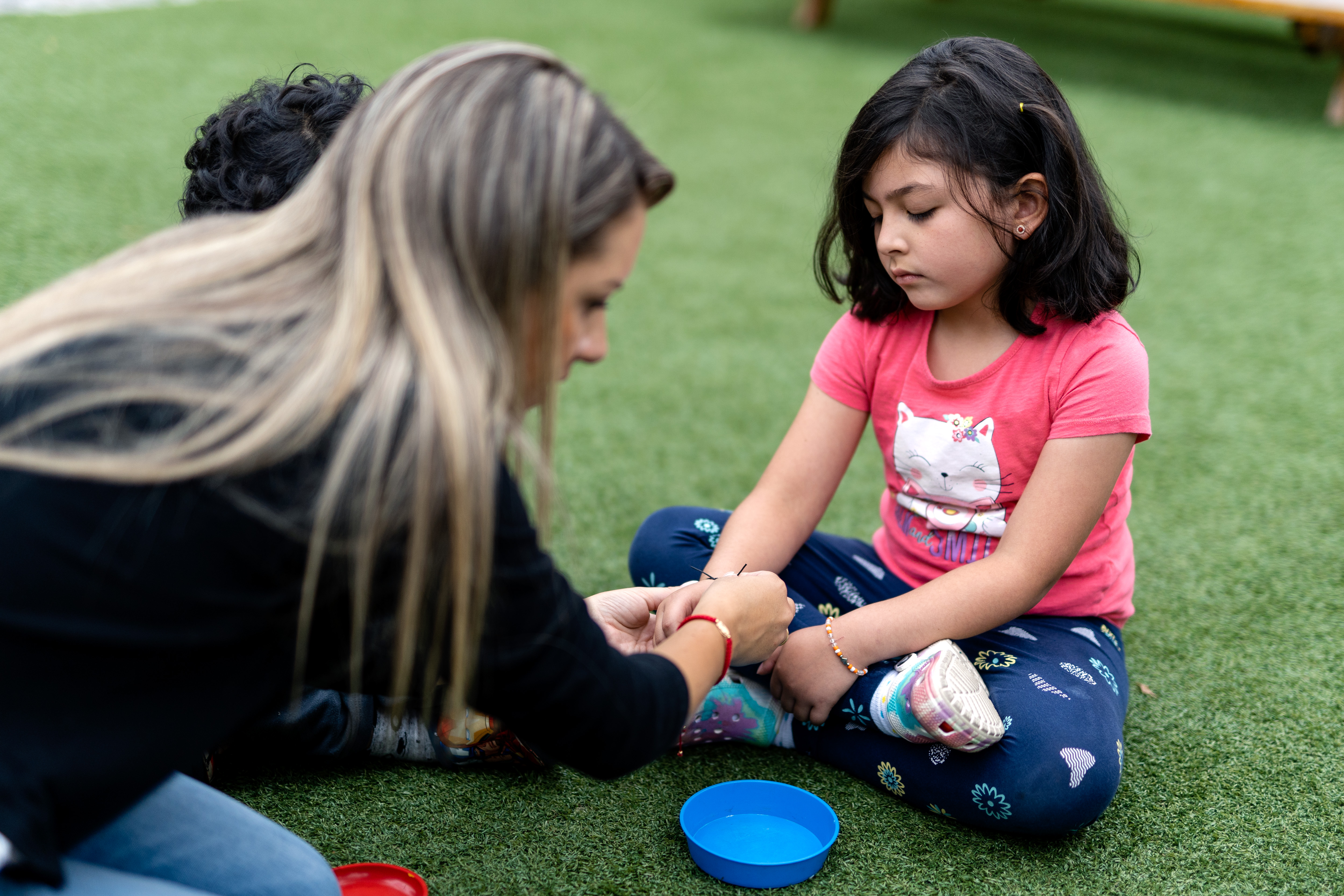 photo of a woman putting a handmade bracelet to a little girl
