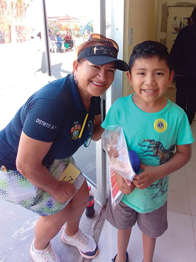 A Lion volunteer shares a moment of kindness with a young boy, showing how local service supports youth and improves well-being.