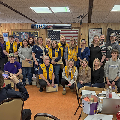 Cook Lions Club members gather indoors, celebrating service achievements and welcoming new members.