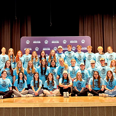 Cook Lions-sponsored Leo Club members gather on stage, celebrating their commitment to youth-led community service.