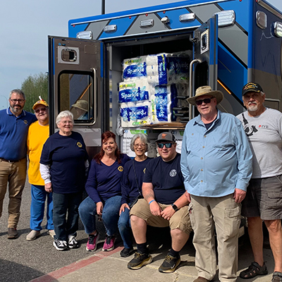 Cook Lions Club members stand by an ambulance loaded with supplies, ready to support their community’s flood recovery efforts.