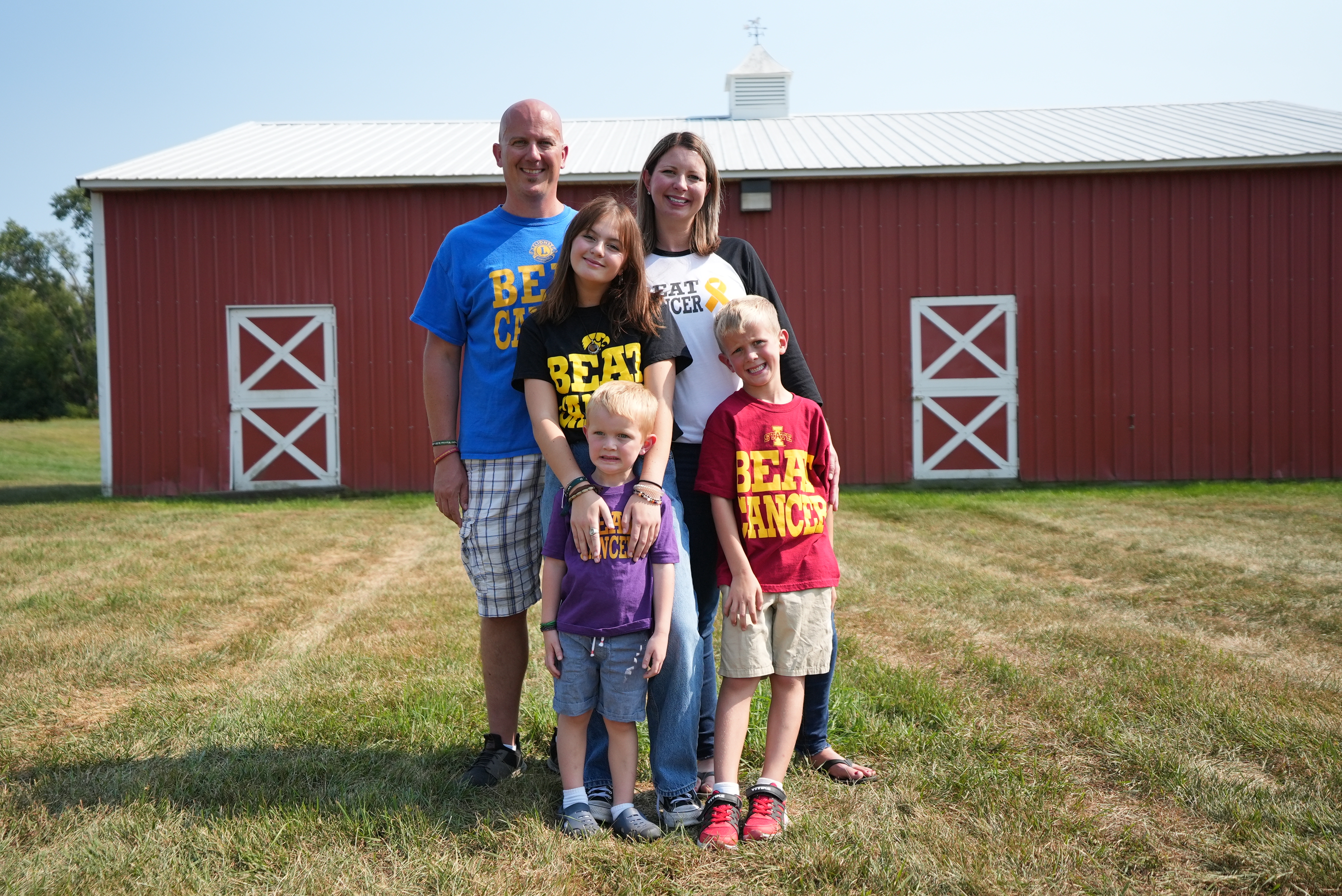 Photo of family - mother, father, son, daughter, in front of barn