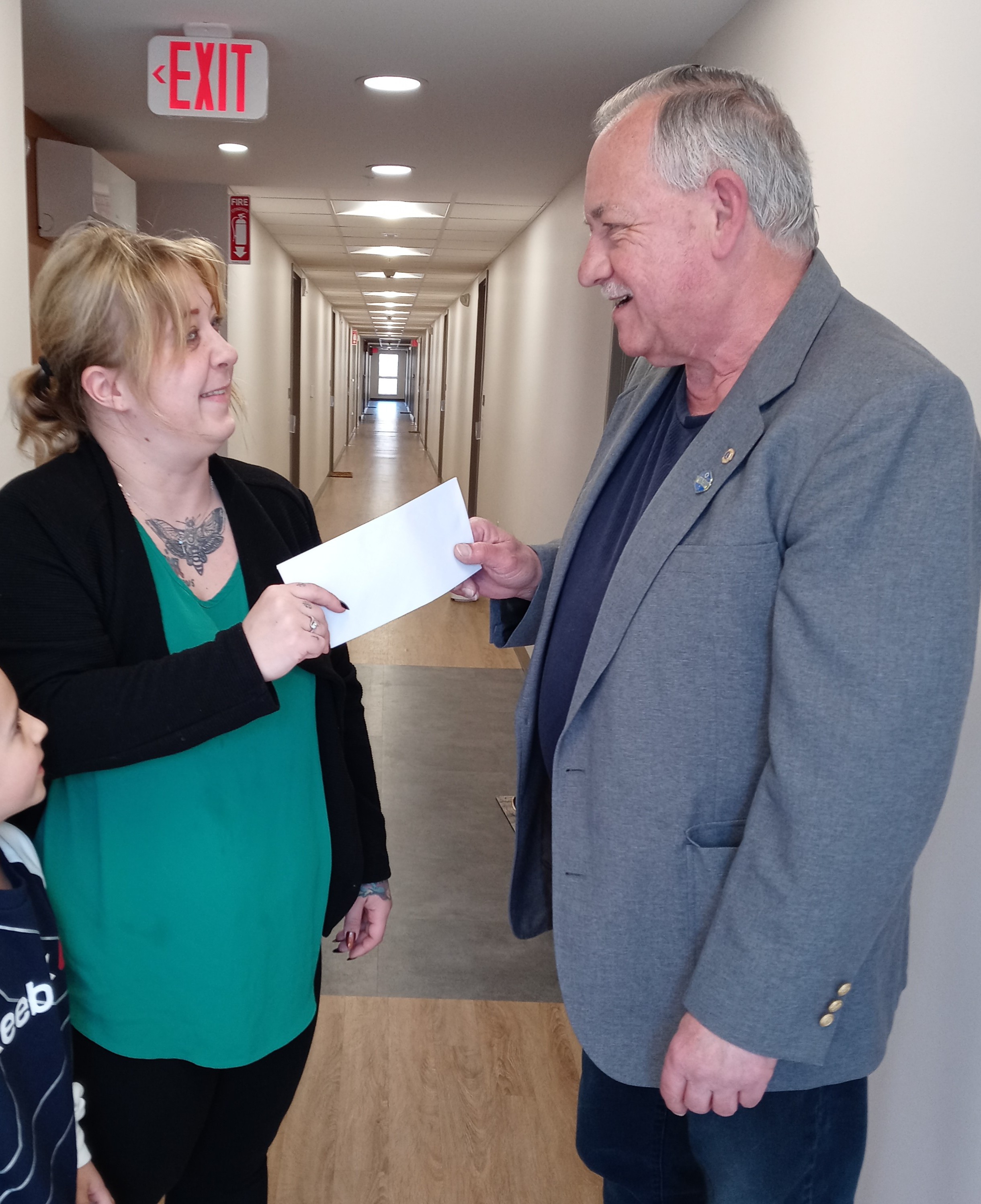 Le Lion John Juhasz remet à Denise Faller un billet de cent dollars dans le cadre de l'acte de bonté gratuite de son club.