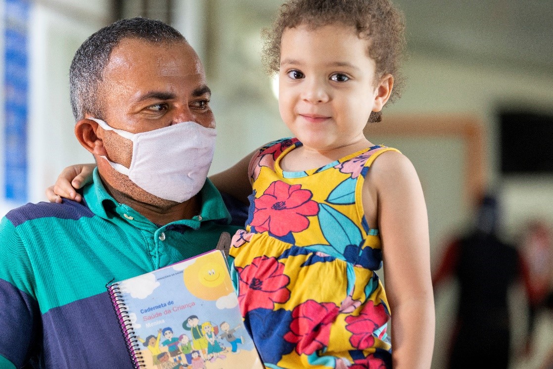 Edicarlos e sua filha Maria mostram sua carteira de vacinação durante uma campanha emergencial de vacinação em Brasília, Brasil. 