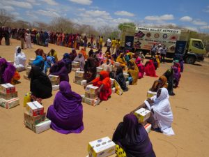 Women wait in the sand for supplies